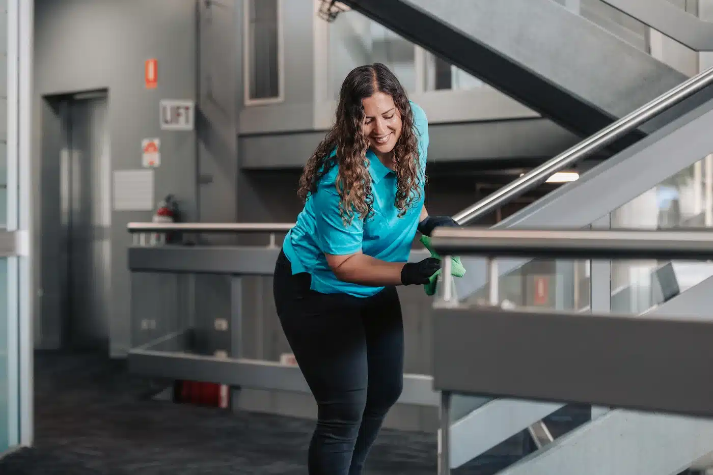 A cleaning professional performing stair cleaning in a modern office in Geelong.